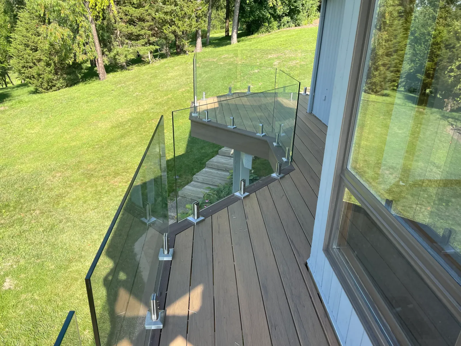 Modern composite deck with frameless glass panel railing overlooking lawn