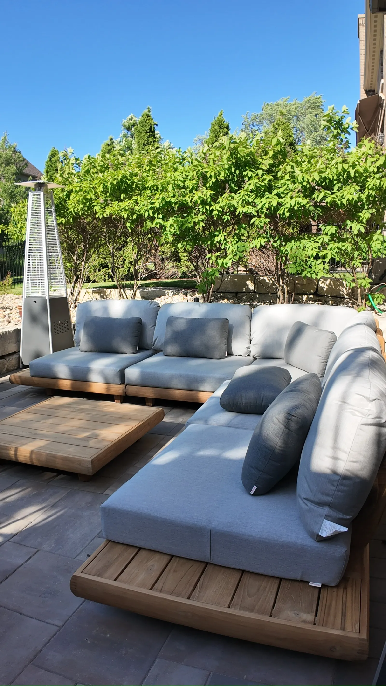 Premium teak outdoor sectional with grey cushions on Unilock paver patio